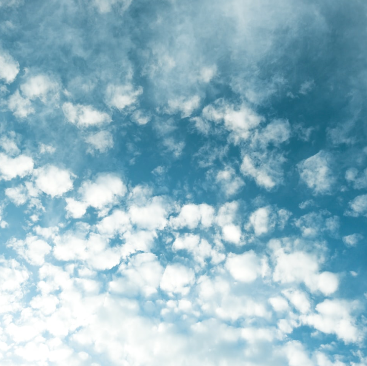 Picture of white fluffy clouds grazing a blue sky.