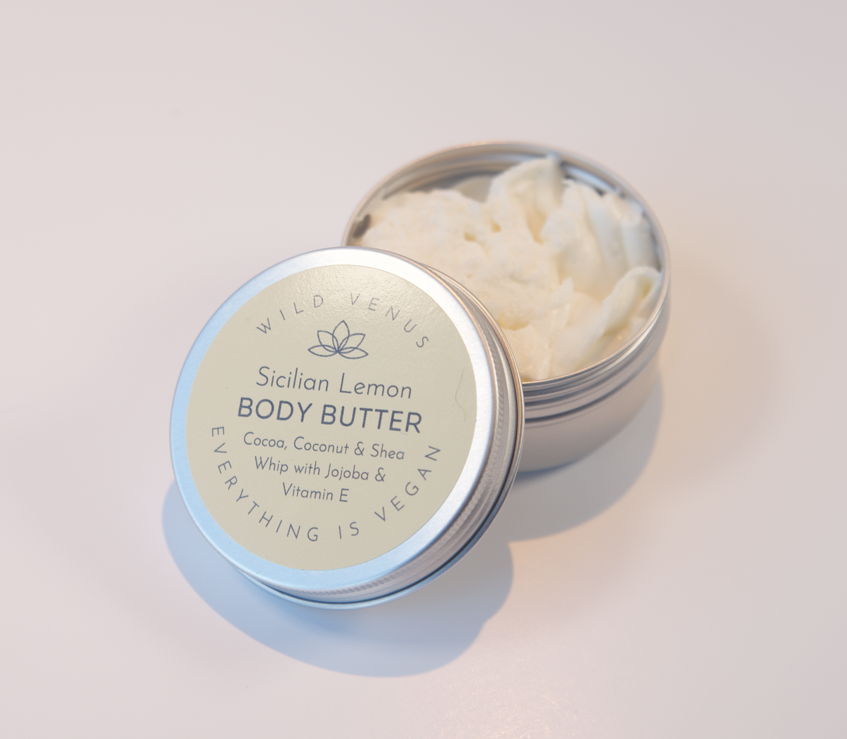 The Sicilian Lemon whipped Body butter shown with the tin lid off revealing the lovely light texture of the triple whipped formula inside. 