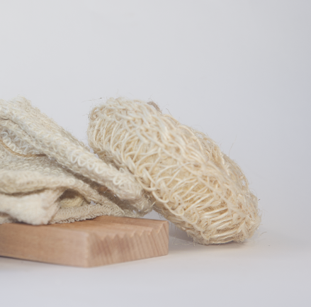 A round sisal sponge sits on top of a soap saver and a soap dish. 